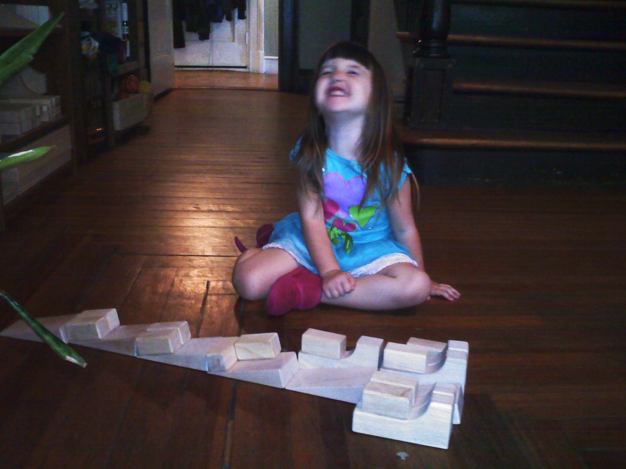 Photo of Livea smiling with her slides made from Hard Rock Maple Wooden Unit Blocks.